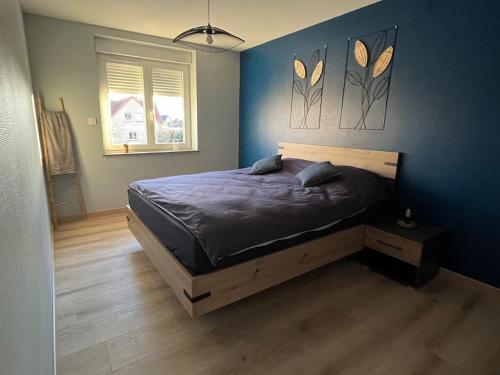 een slaapkamer met een bed met een blauwe muur bij Charmant apt Cosy 5min de Colmar in Sainte-Croix-en-Plaine