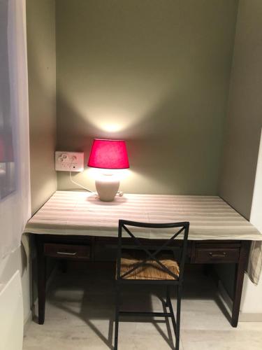 een bureau met een rode lamp en een stoel bij LE TERTRE CAMILLAC 