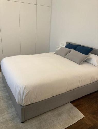 Apartamento elegante céntrico في فيغو: سرير عليه أغطية بيضاء ومخدات زرقاء