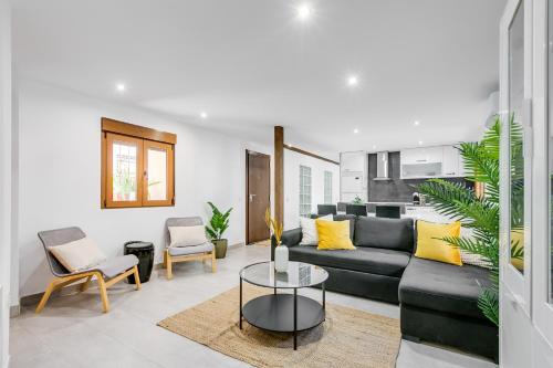 uma sala de estar com um sofá preto e almofadas amarelas em La Casa del Granado em Toledo