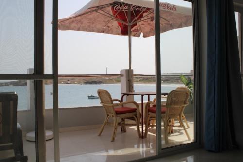 a dining room with a table and chairs and an umbrella at Apartamentos vista ao mar in Praia Baixo