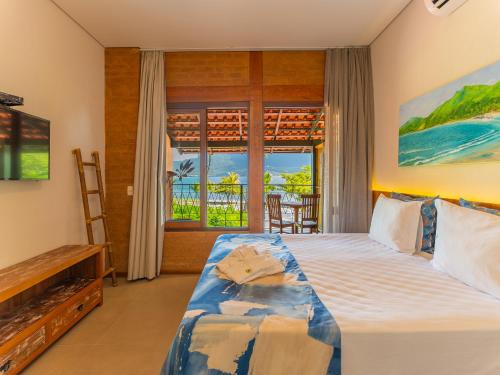a bedroom with a bed and a view of the ocean at Hotel Velas do Engenho in Ilhabela