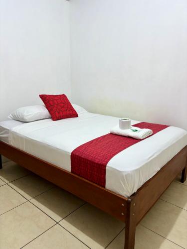 a bed with a red and white blanket on it at Hospedaje Casa Amazónica Iquitos in Iquitos