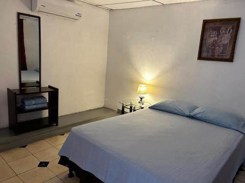 1 dormitorio con cama blanca y espejo en El Callejon Guest House, en León