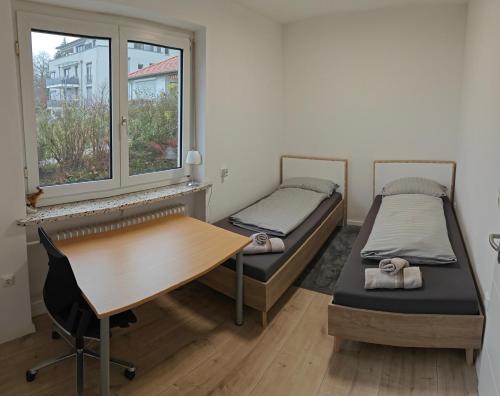 two beds in a room with a desk and window at Ferienwohnung Sorgenfrei - Parkplatz, Balkon & Terrasse in Coburg