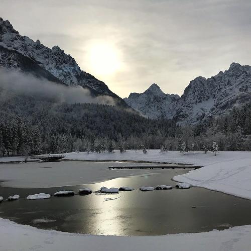 a river with snow and mountains in the background at Pr'Gavedarjo Eco Heritage B&B in Kranjska Gora