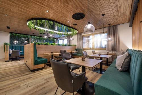 a restaurant with a green couch and tables and chairs at Landrefugium Obermüller SPA & Naturresort 4,5 Sterne in Untergriesbach
