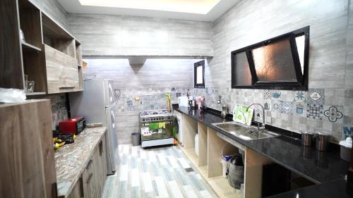 a kitchen with a sink and a refrigerator at Malaz Qaroun - ملاذ قارون in Qaryat at Ta‘mīr as Siyāḩīyah