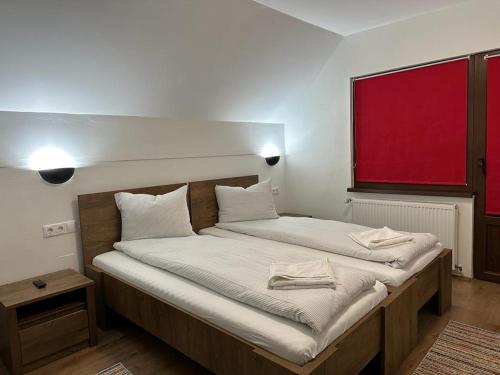 2 camas en una habitación con ventana roja en Casa Demény en Sovata