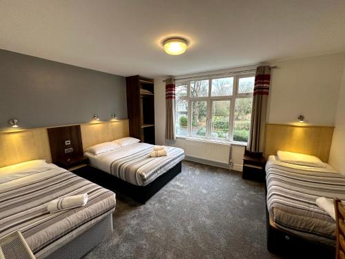 a hotel room with two beds and a window at Gainsborough Lodge in Horley