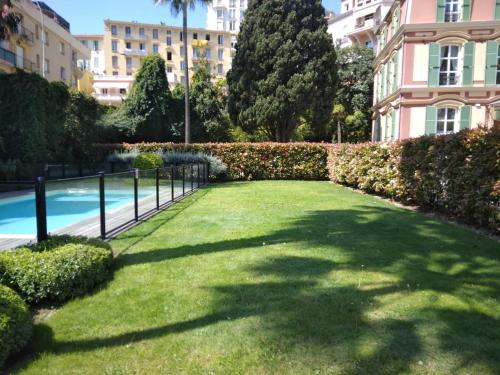 eine Liegewiese vor einem Gebäude mit einem Pool in der Unterkunft Intercontinental Superbe appartement avec piscine in Menton