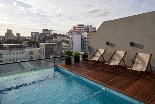 uma varanda com duas cadeiras e uma piscina num edifício em AQ Tailored Suites em Buenos Aires