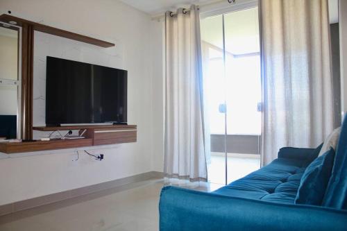 een woonkamer met een blauwe bank en een tv bij Apartamento Novo em Bombinhas a 300 mt da praia Bombas in Bombinhas