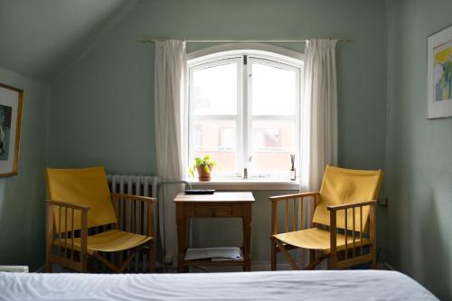 1 dormitorio con 3 sillas, mesa y ventana en Cafe Sallys bed and breakfast en Ribe