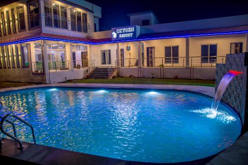 a swimming pool with a fountain in front of a building at Oxygen Resort, Akshi in Alībāg