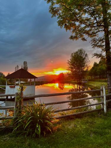 a sunset over a body of water with a fence at Pensiunea Lacul Arșiței in Borşa