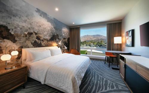 a hotel room with a bed and a desk and a window at Le Meridien Pasadena Arcadia in Arcadia