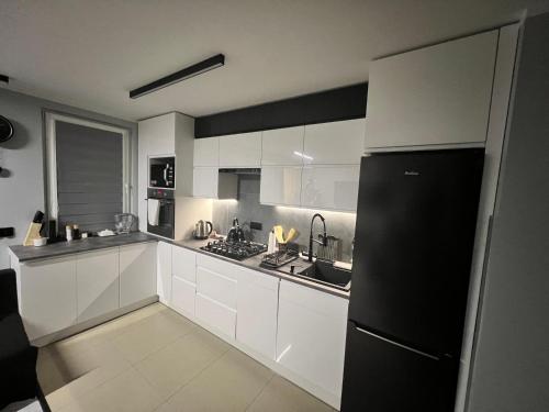 a kitchen with white cabinets and a black refrigerator at Apartament Na Wspólnej in Sosnowiec