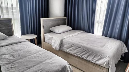 1 dormitorio con 2 camas individuales y cortinas azules en SLEPTOPIA at THE NOVE NONGSA COZY HOOK PREMIUM UNIT WITH AMAZING VIEW, en Nongsa