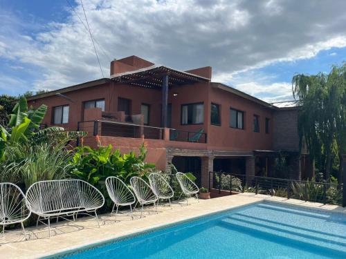 een huis met een rij stoelen naast een zwembad bij Algarrobos del Mirador in Santa Rosa de Calamuchita