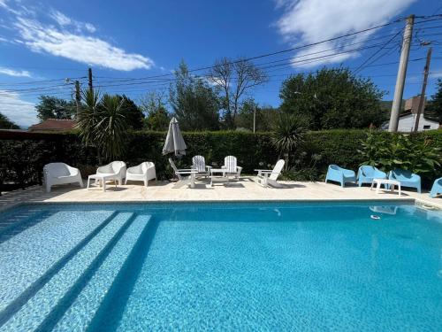 a swimming pool with chairs and a table and umbrellas at Algarrobos del Mirador in Santa Rosa de Calamuchita