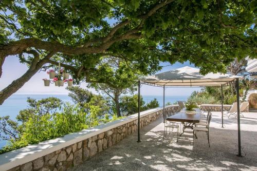 un tavolo e sedie sotto un ombrellone sotto un albero di Luxury Family Amalfi Coast Villa a Piano di Sorrento