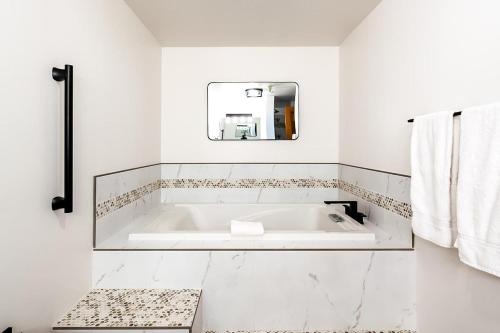 een witte badkamer met een bad en een spiegel bij Cozy Ketchum Condo - Walk to Everything! in Ketchum