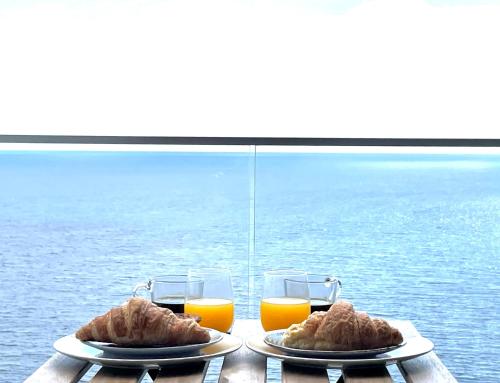 a table with two plates of food and two glasses of orange juice at Ocean Cliff Apartment in Santa Cruz