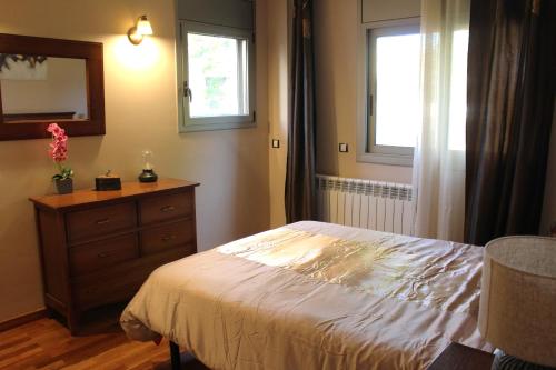 a bedroom with a bed and a dresser and two windows at Residentium Spain -Chalet la Dorada pets friendly in Cambrils