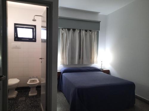 een slaapkamer met een bed en een badkamer met een toilet bij Hotel Marino in Villa Gesell