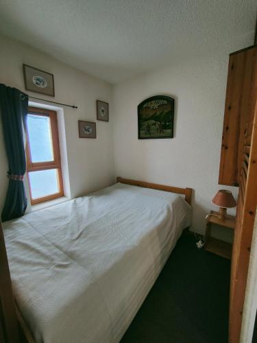 une chambre avec un lit blanc et une fenêtre dans l'établissement Arc 2000 - Charmant appartement 4 personnes, chambre séparée, calme et en plein centre, à Bourg-Saint-Maurice
