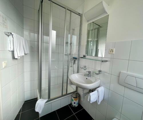 a white bathroom with a sink and a shower at Hotel Movieworld in Spiez