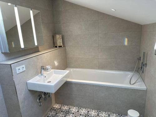 La salle de bains est pourvue d'un lavabo et d'une baignoire. dans l'établissement muchhome LUXURY APARTMENTS - Apartment Vintage mit Balkon und Seeblick, à Gmund am Tegernsee
