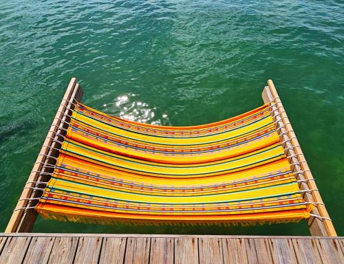 uma poltrona colorida sentada numa doca na água em The Sea Monkey em Bocas del Toro