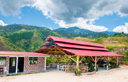 un restaurant avec un toit rouge et des montagnes en arrière-plan dans l'établissement Los Nevados Ecolodge, à Gigante