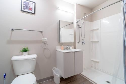 a white bathroom with a toilet and a shower at McCormick 2br/2ba Oasis with Optional Parking, Patio, Gym for up to 6 guests in Chicago