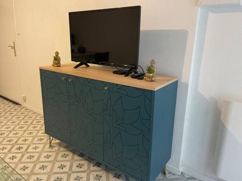 a blue dresser with a television on top of it at Au Coeur de la Cité Médiévale in Montluçon