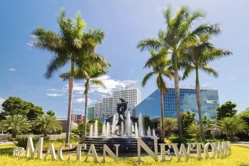 a monument in front of a city with palm trees at Mactan Newtown Beach Condo in Mactan