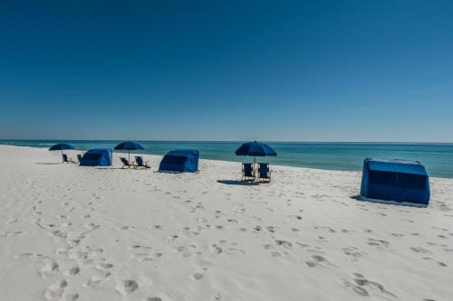 een groep stoelen en parasols op een strand bij Portofino Tower1-908 Beachfront Sunrise Views in Pensacola Beach