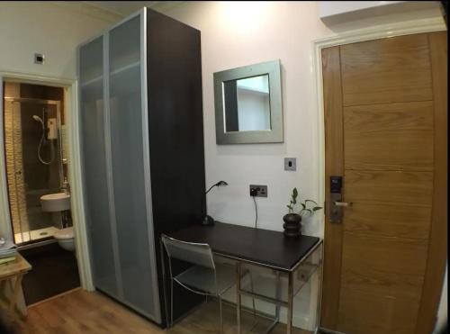 een bureau in een kamer met een spiegel en een badkamer bij Soho China Town Rooms in Londen