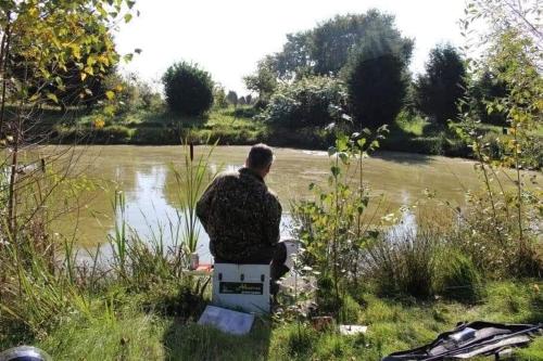 a man sitting on a bench next to a river at Ottenskamp4 en Het Achterhuis in Siebengewald