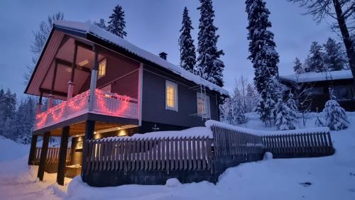 Una casa en la nieve con luces de Navidad. en Villa Magnolia 1 Himos, en Jämsä