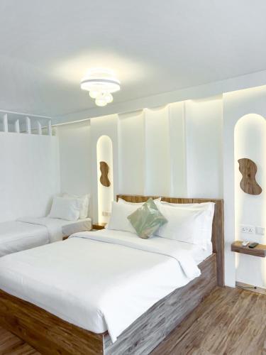 two beds in a bedroom with white walls and wood floors at Sandy Heaven Maldives in Gulhi