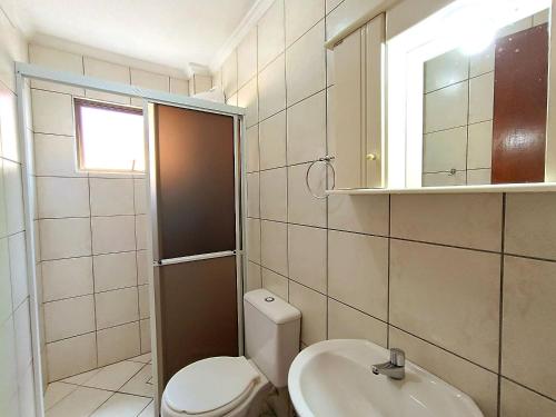 een badkamer met een toilet, een wastafel en een spiegel bij 206-CDB Dpto a 100m del mar de Bombas in Bombinhas