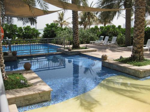 a swimming pool with palm trees in a resort at Royal Club By RVHR, Palm Jumeirah in Dubai