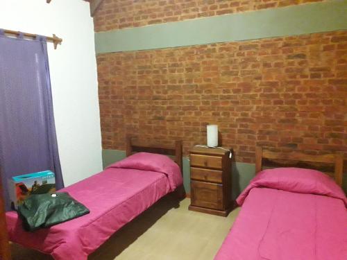 a bedroom with two beds and a brick wall at Mi lugar in Piriápolis