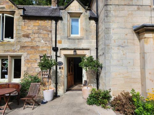 an old stone house with a door and a table and chairs at Mulgrave Country Cottage in Whitby