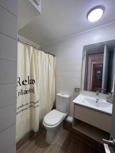 y baño con aseo, lavamanos y cortina de ducha. en Dpto 3D 2B + Quincho propio By Terrabahia, en Bahía Inglesa