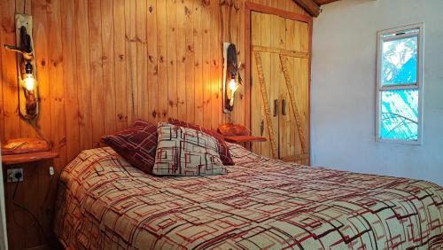 Un dormitorio con una cama con paredes de madera y una ventana en Ensueño del alma en Villa Pehuenia