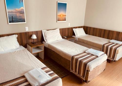 a hotel room with three beds in a room at Hotel Prudente RP in Ribeirão Preto